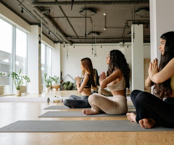 Group of diverse people stretching on yoga mats in a bright studio.